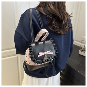 Detail of sweet girl backpack with lace edges, pink satin bow, and heart pendant charm