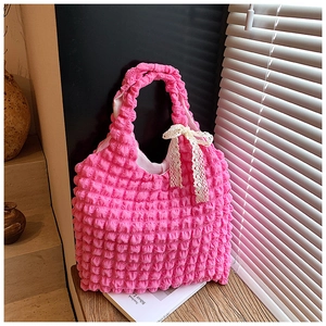 Detail of pink bubble texture tote bag featuring a delicate white lace bow accessory