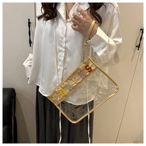 Detail of transparent PVC clutch bag with gold trim and rainbow SNACKS embroidery