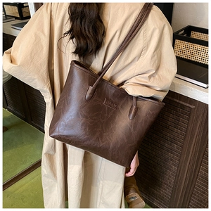 Detail of dark brown tote bag featuring retro cracked texture and FASHION embossed logo