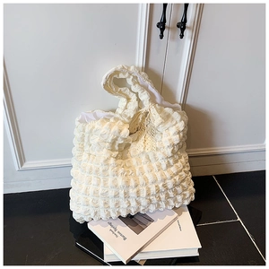 Detail of cream white tote bag with bubble pleat texture and white lace bow decoration