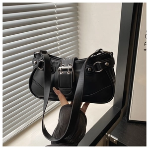 Detail shot of the silver metal buckle and grommets on a black shiny shoulder bag