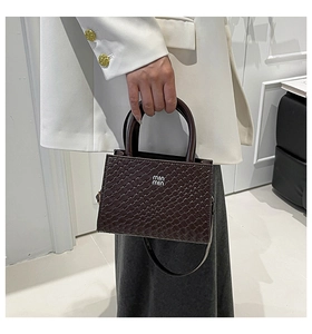 Close-up of woven texture and silver hardware on a dark brown crossbody mini bag