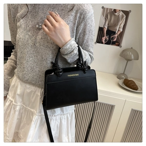 Black matte leather tote bag with knotted handles shown in a minimalist interior setting