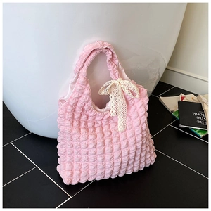 Detail of pink bubble textured fabric handbag with white lace bow decoration