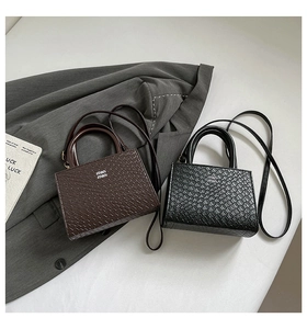 Detailed view of woven texture small square bags in black and brown with logo metal charm