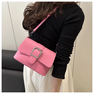 Détail d'un sac bandoulière en cuir rose avec boucle argentée porté par un mannequin