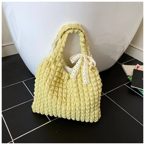 Detail of yellow seersucker handbag featuring a delicate white lace bow accessory