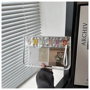 Close-up of clear PVC snack bag with colorful SNACKS embroidery and silver trim