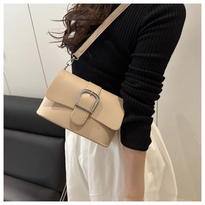 Détail d'un sac à bandoulière beige minimaliste avec une grande boucle argentée sur un modèle