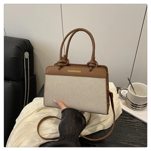 Detail of canvas and brown leather tote showing gold embossed Fashion Bag logo and handle