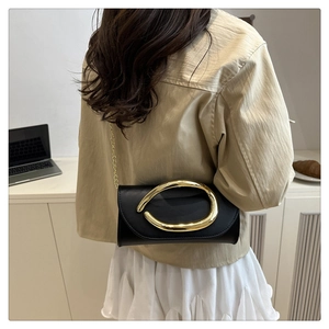 Détail d'un sac bandoulière noir en cuir avec une boucle en métal doré abstrait et chaîne