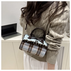 Detailed view of stylish polka dot bow handbag with plaid patterns and ruffle trim