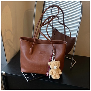 Detailed macro of the vintage brown leather tote bag with fashion embossed label and plush charm