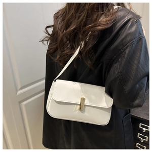Detail of white patent leather shoulder bag with gold metal buckle on a black jacket