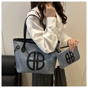 Detail of blue denim tote bag with interlocking logo and matching pouch set