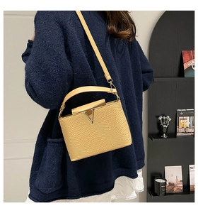 Détail du sac à main beige en cuir texturé avec boucle métallique dorée en forme de V