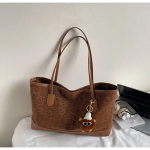 Detail of leopard print tote bag with plush monster charm and smooth leather handles