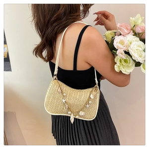 Detail of straw woven shoulder bag with pearl shell charms and gold chain accessories