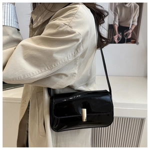 Close-up of black glossy patent leather handbag with elegant gold metal buckle detail