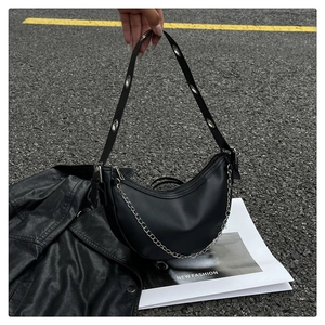 Detail of black crescent tote bag with silver chain and metal eyelet shoulder strap