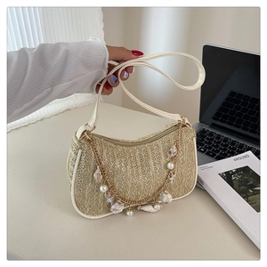 Detail of straw hobo bag with pearl shell charms and a golden metal chain accent