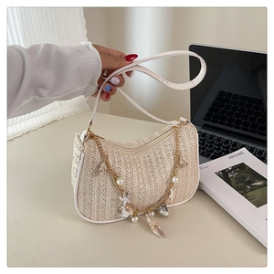 Detailed view of the seashell and pearl chain accents on the beige woven shoulder bag