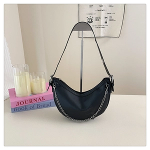 Detailed macro of the black crescent bag showing matte leather texture and silver chain