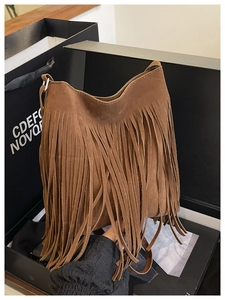 Close-up of brown suede shoulder bag featuring long vintage fringes and metallic clasp