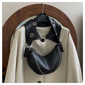Close-up of black half-moon shoulder bag with wide grommet strap and silver chain detail