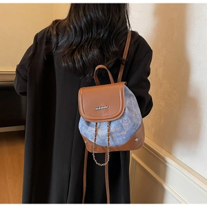 Close-up of mini backpack featuring cat prints and a brown leather flap with metal logo