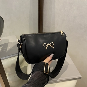 Chic black crossbody bag with a gold bow accent and wide fabric shoulder strap