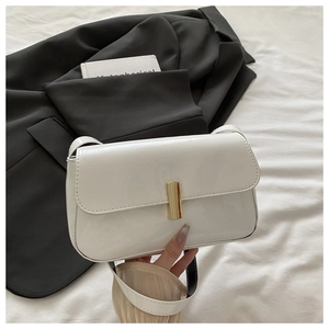 Macro shot of white patent leather shoulder bag with a gold rectangular metal lock