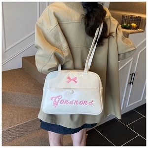 Close-up of white patent leather tote bag featuring pink embroidered bow and text design
