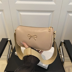 Beige faux leather crossbody bag with metal bow detail and adjustable wide strap