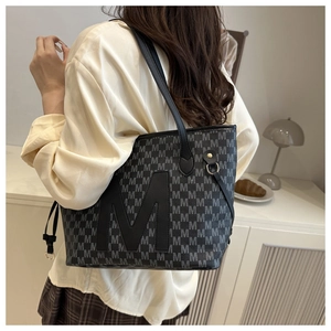 Close-up of a large-capacity tote bag with M-letter monogram print and leather shoulder straps