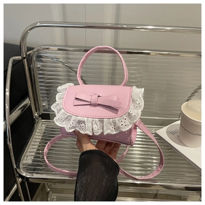 Detailed view of pink crossbody bag with white lace trim and decorative bow accent