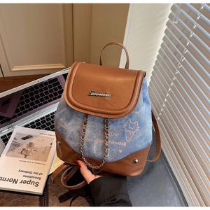 Detail of a mini patchwork denim and brown leather backpack with cartoon cat print