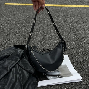 Black vegan leather crescent hobo bag with silver chain and metal eyelet strap on street
