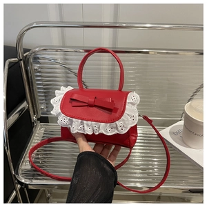 Detail of red PU leather mini bag featuring layered white lace trim and bow accent