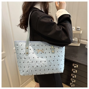 Détail du sac matelassé bleu clair avec imprimé nœuds noirs et boucle dorée