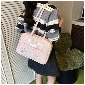 Pink glossy leather tote bag with bow embroidery shown in a cozy lifestyle setting