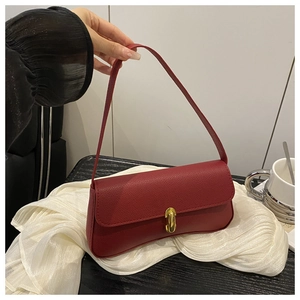 Détail macro du cuir grainé rouge et du fermoir doré de luxe sur le sac à bandoulière