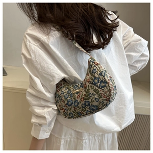 Detailed close-up of floral jacquard fabric and gold hardware on half-moon bag