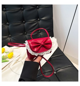 Detailed close-up of a mini red shoulder bag with lace edges and a large sweet bow accent