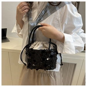 Detail of black sequined bucket bag featuring drawstring satin lining and elegant texture