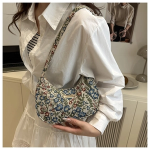 Close-up of vintage floral jacquard shoulder bag with metallic logo and crescent shape