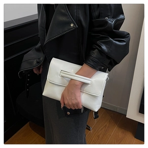 Détail de la pochette enveloppe en cuir blanc brillant avec chaîne et dragonne