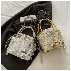 Close-up of silver and gold sequin bucket bags with satin drawstring liners on black fabric