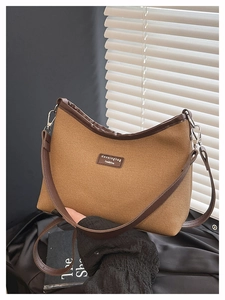 Detail of a brown canvas hobo bag with dark leather trim and silver metal hardware hooks